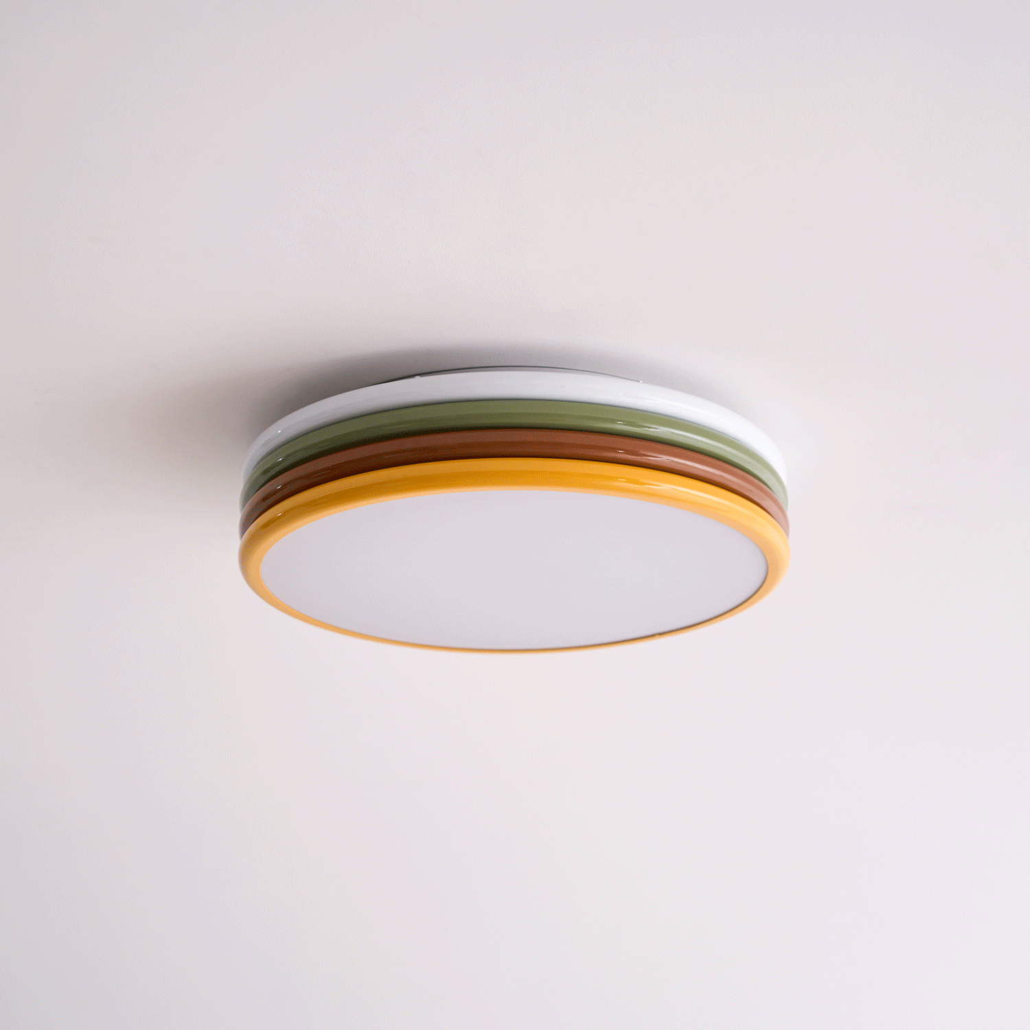 Unlit Clérachic ceiling light on a pale pink-white ceiling, its green and red-brown tiers above a frosted diffuser.