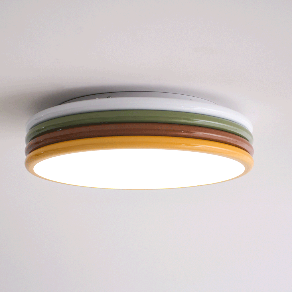 Low side view of this Clérachic ceiling light lit, with a bright glow along its yellow rim and a white top ring above.