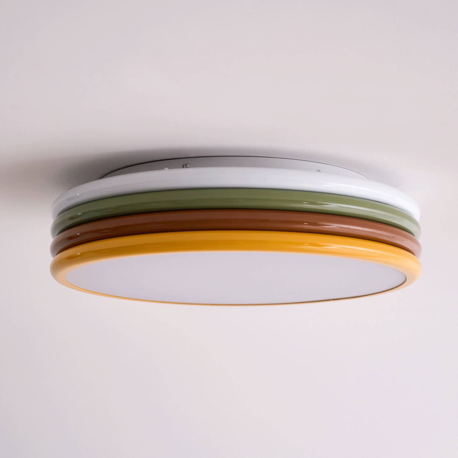 Low side view of this unlit Clérachic ceiling light, its canopy plate, four coloured rings and frosted diffuser all showing.