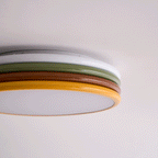 Edge-on close view of this Clérachic ceiling light's white, green, red-brown and yellow rings above the frosted diffuser.