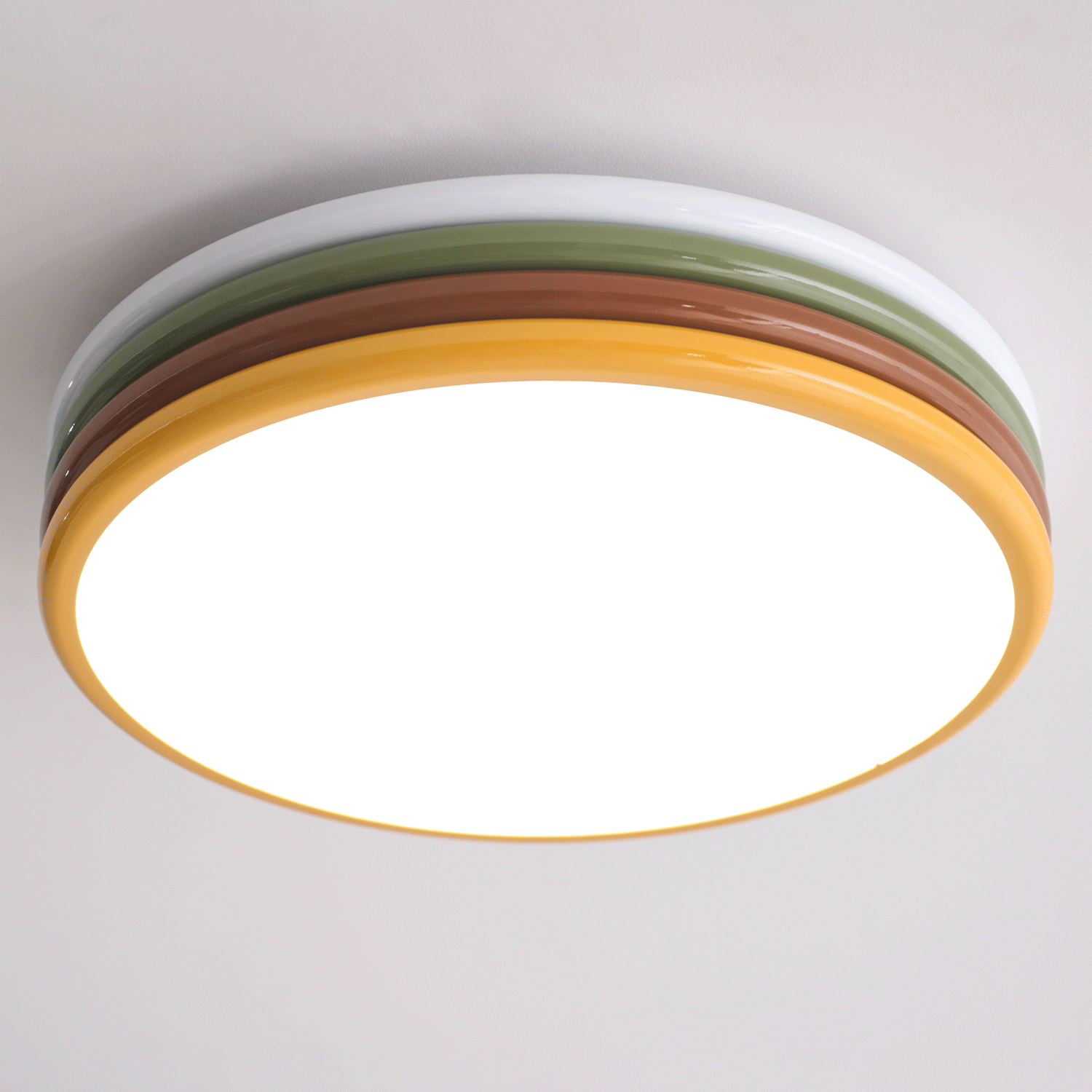 Underside of this lit Clérachic ceiling light, a bright round diffuser inside a golden-yellow ring and the layered tiers above.