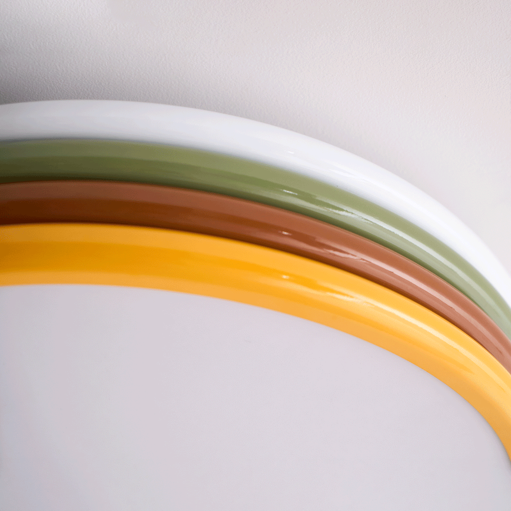 Close crop of the white, green, red-brown and yellow rings curving over the diffuser on this Clérachic ceiling light.