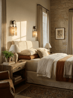 Two Clérachic sconces flank a bed with rust and cream bedding, one lit above the headboard and one on the stone-faced wall.