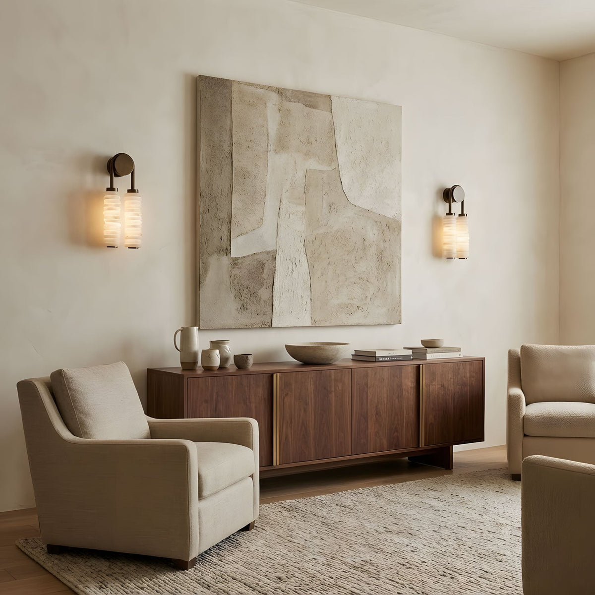 Two Clérachic sconces lit on either side of a large abstract canvas, over a walnut sideboard and a cream armchair.