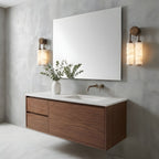 Two Clérachic sconces on a concrete-effect bathroom wall, flanking a large frameless mirror above a floating walnut vanity.