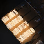 Four Clérachic sconces lit on a dark workshop table, light glowing through the veined alabaster discs.
