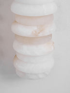 Close view of unlit alabaster discs on a Clérachic sconce, pale and softly pink-white with natural veining.