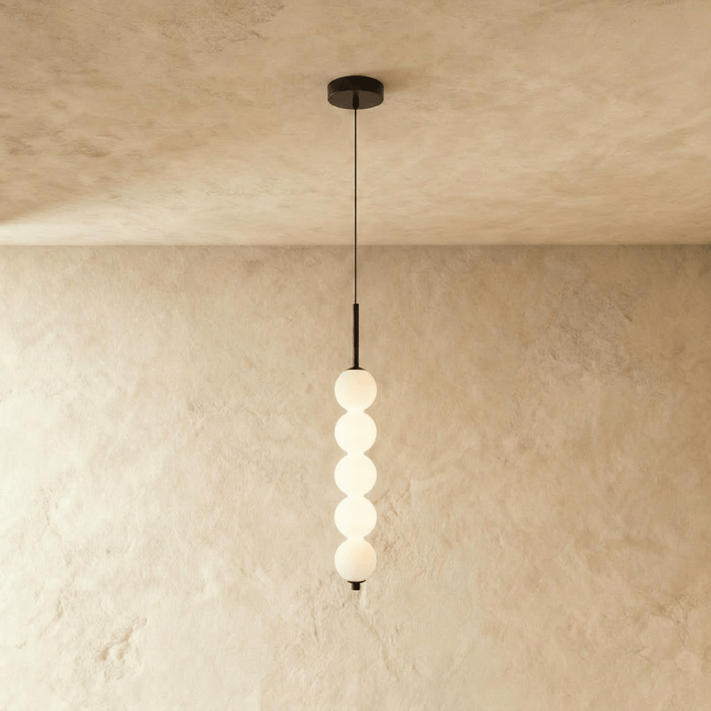 Clérachic black five-ball pendant with lit opal glass spheres hanging below a round black ceiling canopy.