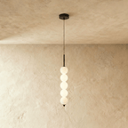 Clérachic black five-ball pendant with lit opal glass spheres hanging below a round black ceiling canopy.