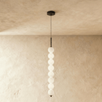 Clérachic black eight-ball pendant, a tall column of glowing opal glass spheres on a thin cord and black stem.