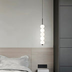 Clérachic black five-ball pendant lit beside a pale oak headboard, with grey wardrobe doors and a wall socket behind.