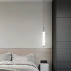 Clérachic black five-ball pendant hung high beside an oak headboard, with soft grey bedding and dark wardrobe panels.