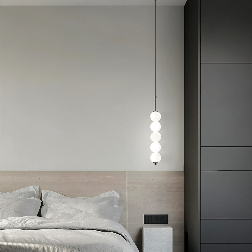 Clérachic black five-ball pendant hung high beside an oak headboard, with soft grey bedding and dark wardrobe panels.