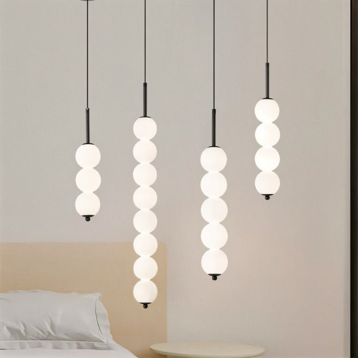 Four Clérachic black pendants in different lengths, with three, eight, five and four opal spheres, glowing together.
