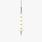 Chrome and white Clérachic pendant of five stacked ribbed glass discs on a slim rod, lit and hung on a plain white backdrop.