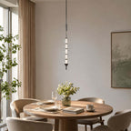 Black and clear Clérachic pendant, its stacked glass discs glowing over a round dining table with flowers and a stack of books.