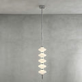 Chrome and white Clérachic pendant of stacked ribbed frosted discs, lit and hanging from its canopy against a grey plaster wall.