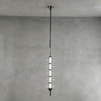 Black and clear Clérachic pendant with stacked clear glass discs around a dark core, hung against a grey plaster wall.