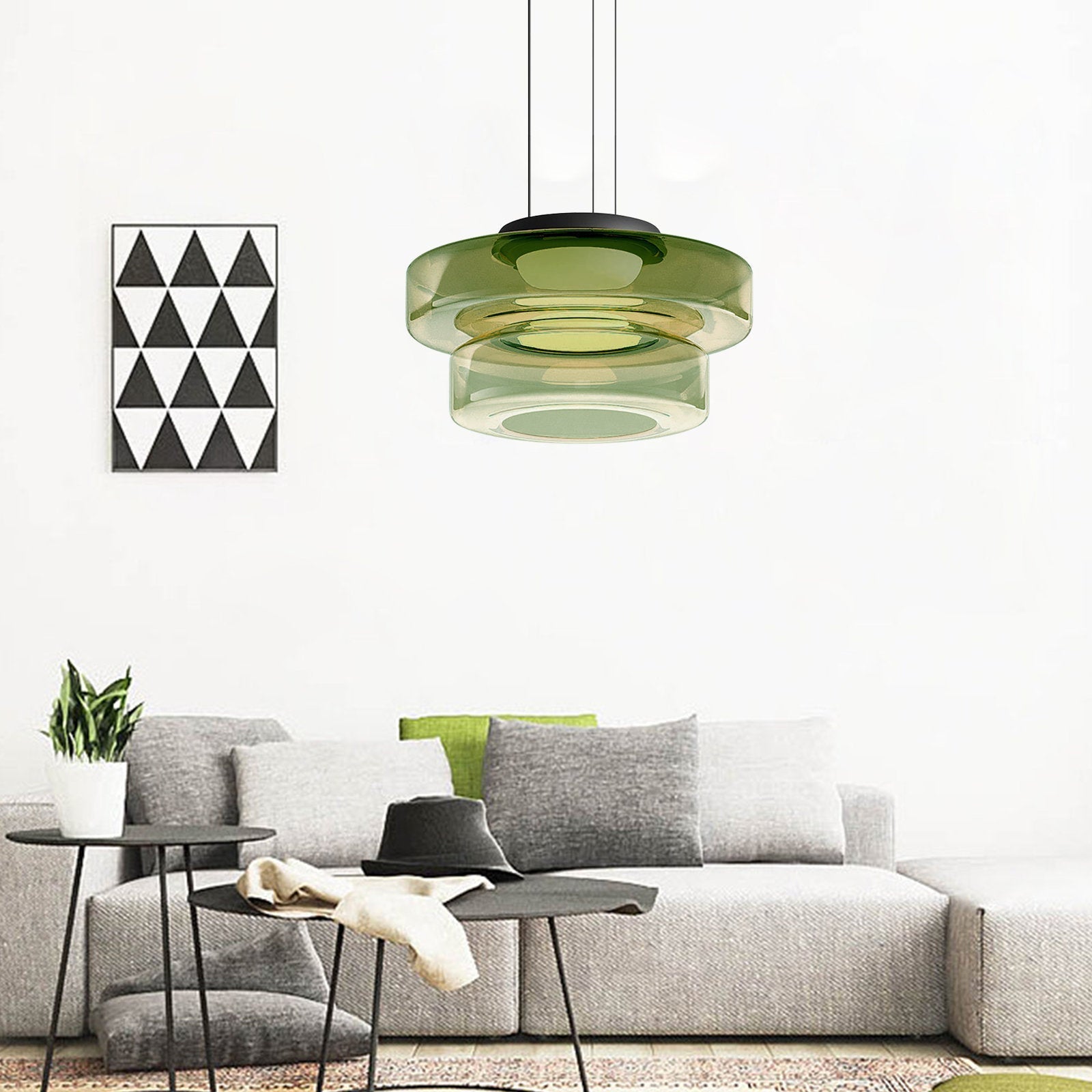 Green Clérachic Stacked Glass Disc Pendant Light lighting a living room above a grey sofa and two low black side tables.