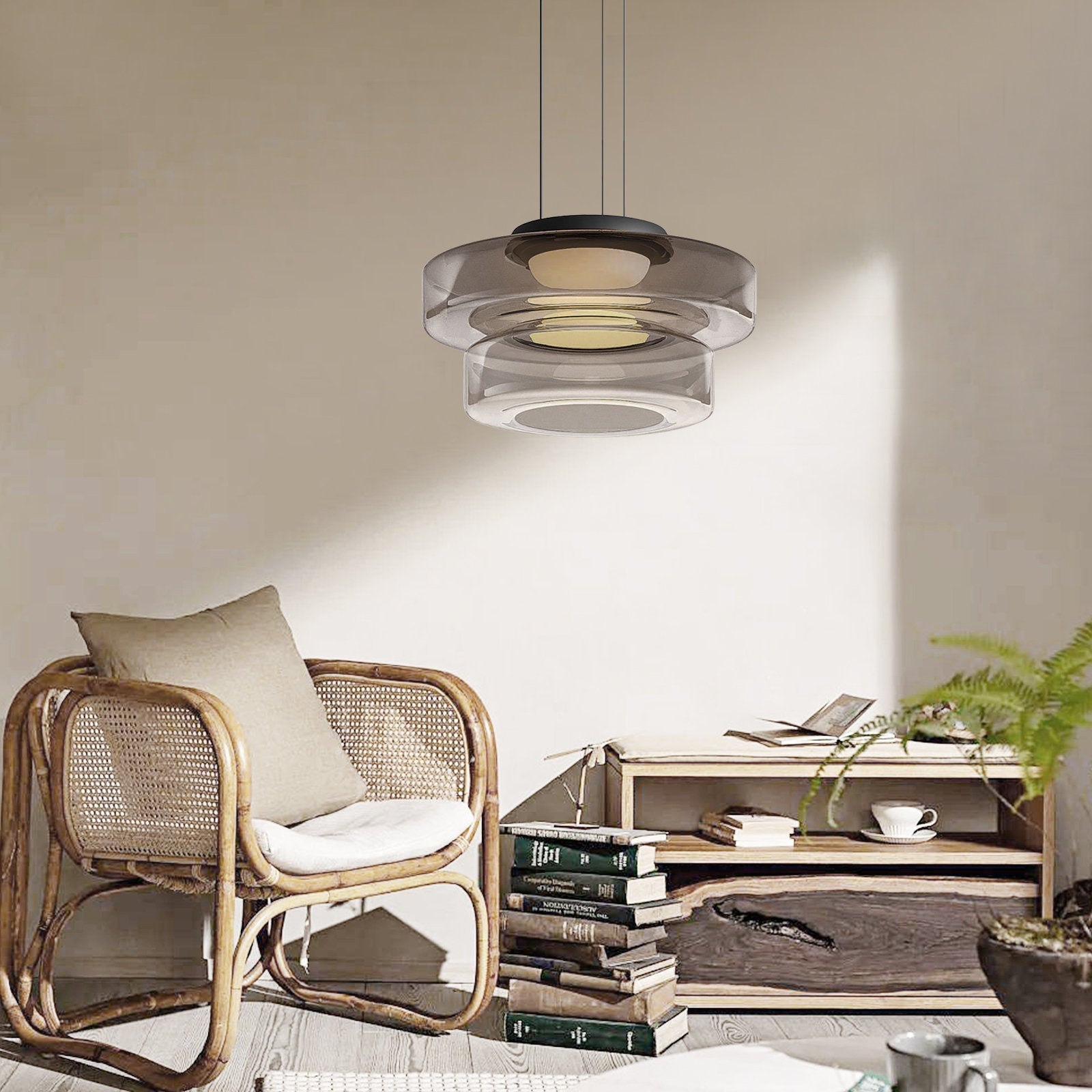 Two-tier Smoke Gray Clérachic Stacked Glass Disc Pendant Light lighting a reading corner with a rattan chair and stacked books.