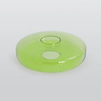 The wider green glass disc of the Clérachic Stacked Glass Disc Pendant Light seen at a low angle, its rolled rim catching light.