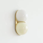 Slightly angled Clérachic sconce with a white upper globe and a pale cream lower globe on a gold-toned plate.