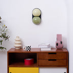 Above a retro walnut sideboard with a yellow cupboard door, this Clérachic wall light has pale yellow and sage-green globes.