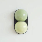 Black-backed Clérachic sconce in pale sage over a soft lime tone, photographed straight on against a mint-white wall.