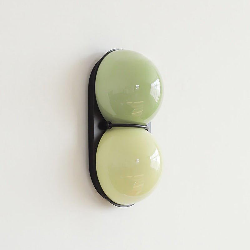 Sage-green over pale lime on a black backplate, this Clérachic wall light hangs on a white wall in soft daylight.