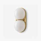 Brass-coloured plate and a slim bar between two white globes, this Clérachic wall light is photographed on a clean white ground.