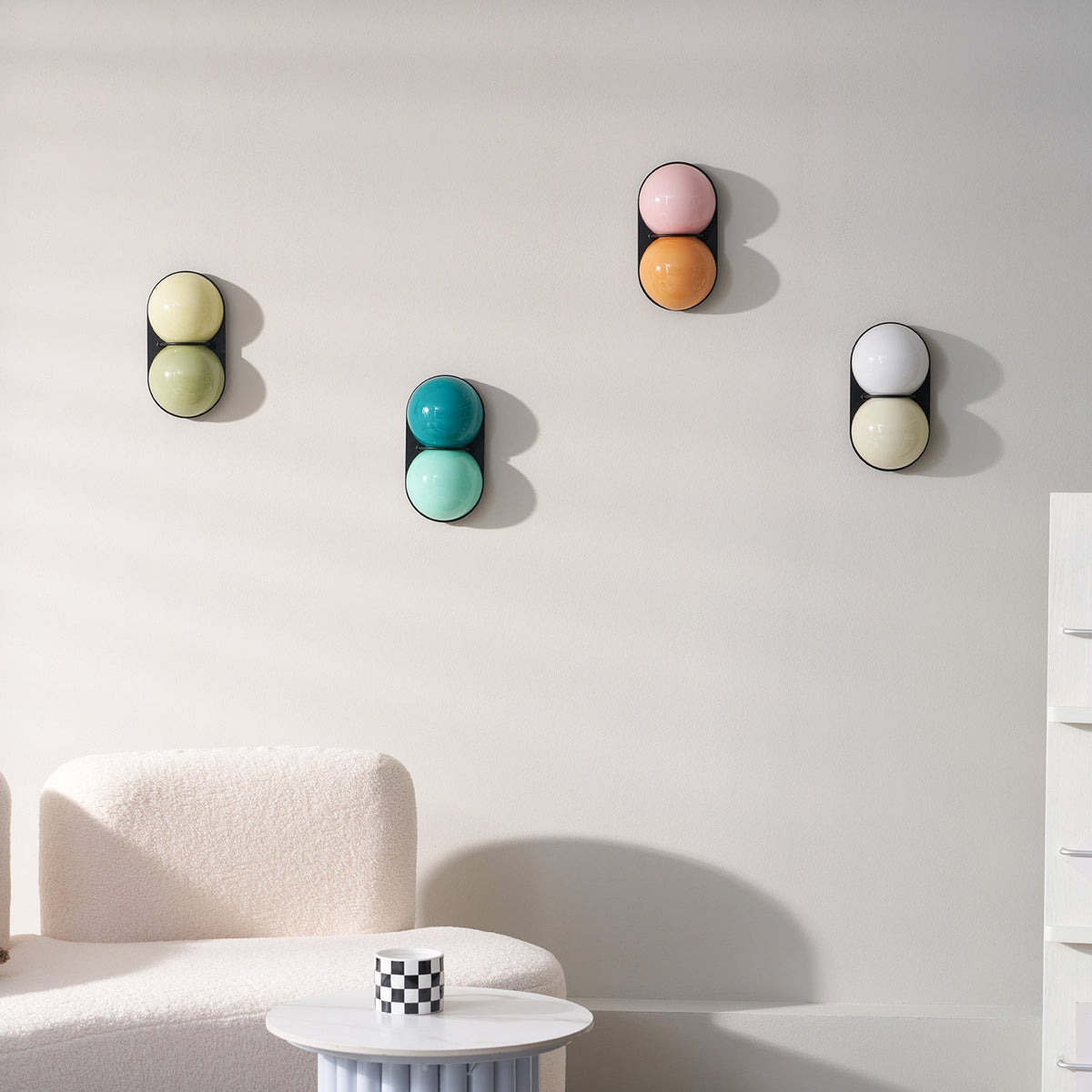 Teal-and-aqua, sage, pink-orange and white globes make up this group of Clérachic wall lights on a white wall.
