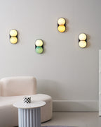 Four Clérachic wall lights lit warm above a bouclé sofa and a fluted side table with a checked cup.