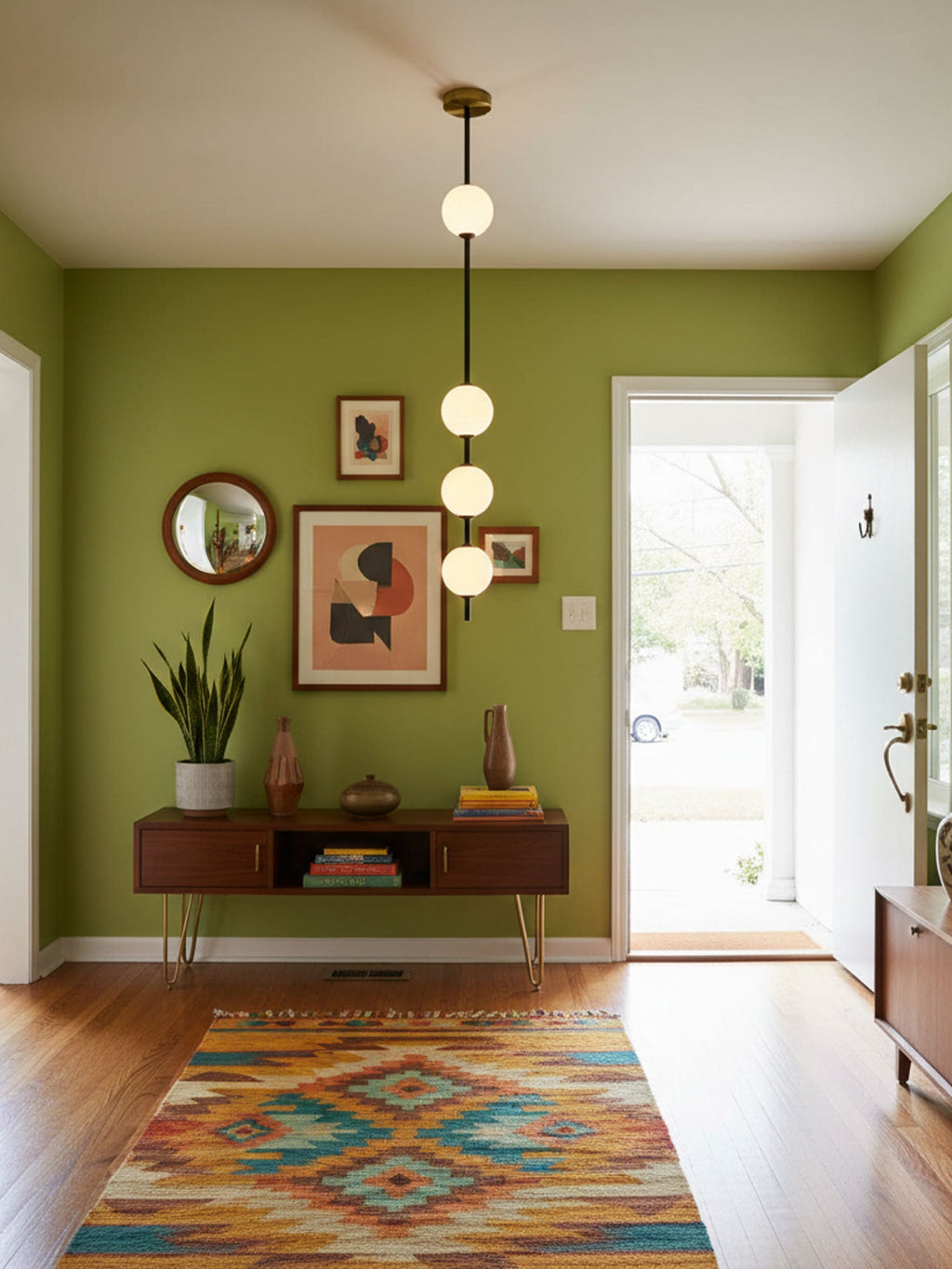 Four-globe Clérachic pendant with a brass column in an entrance hall with olive-green walls, framed prints and a colourful patterned rug.