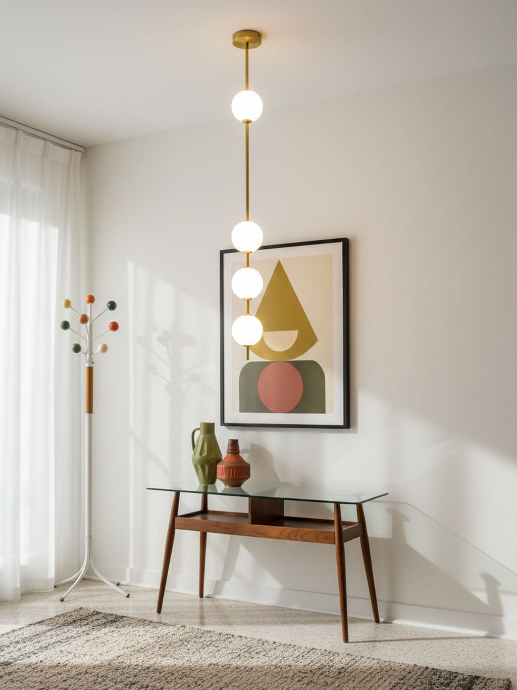 A Clérachic brass-column pendant with four globes hanging beside a framed geometric print above a glass-topped console table.