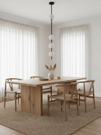 Clérachic pendant with a black column and four soft white globes in a dining room, with sheer curtains and a wooden table below.