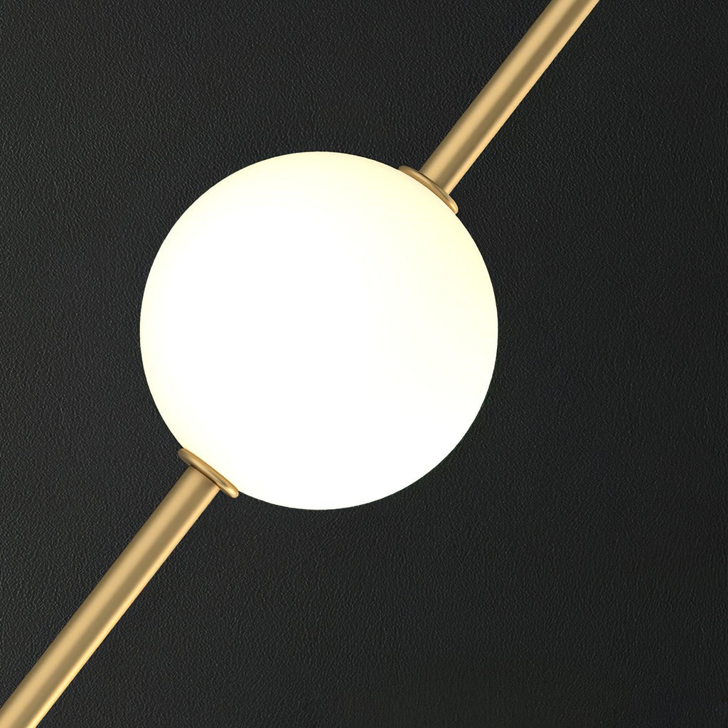 Close view of one smooth, softly glowing opal globe held on a slim brass rod, from this Clérachic pendant, on a dark background.