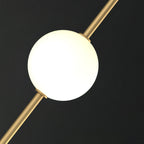Close view of one smooth, softly glowing opal globe held on a slim brass rod, from this Clérachic pendant, on a dark background.