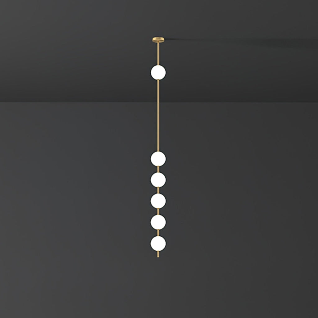 Clérachic pendant with five opal globes lit white on a brass column, against a dark charcoal wall and ceiling.