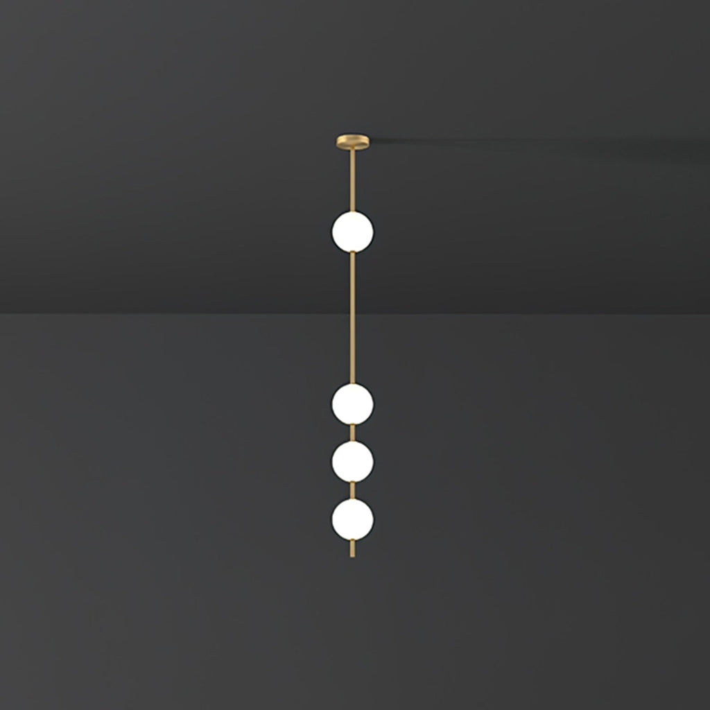 Four lit opal globes on a brass column, a Clérachic pendant hung from a small brass plate against a dark grey wall.