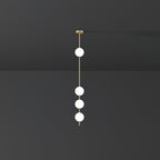 Four lit opal globes on a brass column, a Clérachic pendant hung from a small brass plate against a dark grey wall.