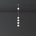 Clérachic brass-column pendant with five lit globes, larger in the frame, against a charcoal wall.