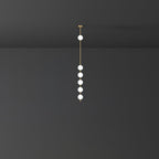 Clérachic pendant with six globes on a slender brass column, the group clustered low, against a dark wall.