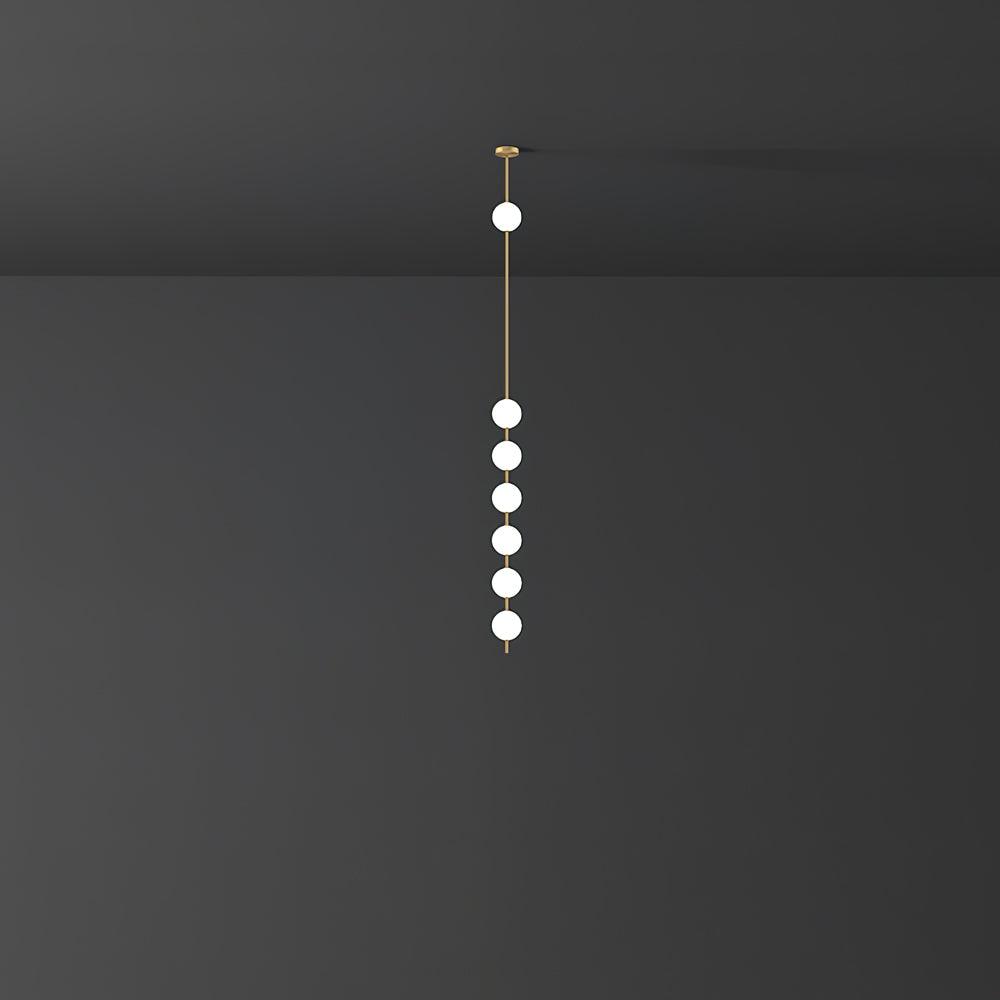 Six lit opal globes on a brass column, a Clérachic pendant seen at a distance against a charcoal wall.