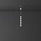 Six lit opal globes on a brass column, a Clérachic pendant seen at a distance against a charcoal wall.