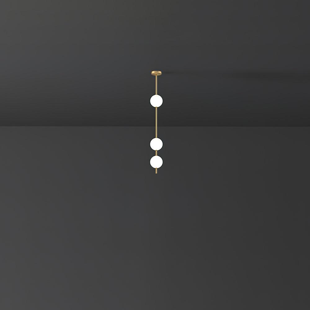 Three opal globes glowing on a short brass column from a Clérachic pendant, set in a dark grey room.