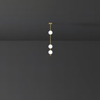 Three opal globes glowing on a short brass column from a Clérachic pendant, set in a dark grey room.