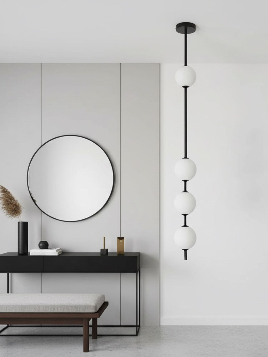 Black-column Clérachic pendant with four globes beside a large round mirror, a slim black console and a cushioned bench.