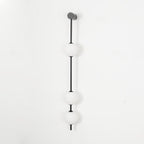 The Clérachic Stacked Globe Wall Sconce in matte black, unlit, three opal globes shown straight-on against white.
