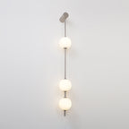 The Clérachic Stacked Globe Wall Sconce in brushed nickel, lit, three globes glowing on a plain white backdrop.