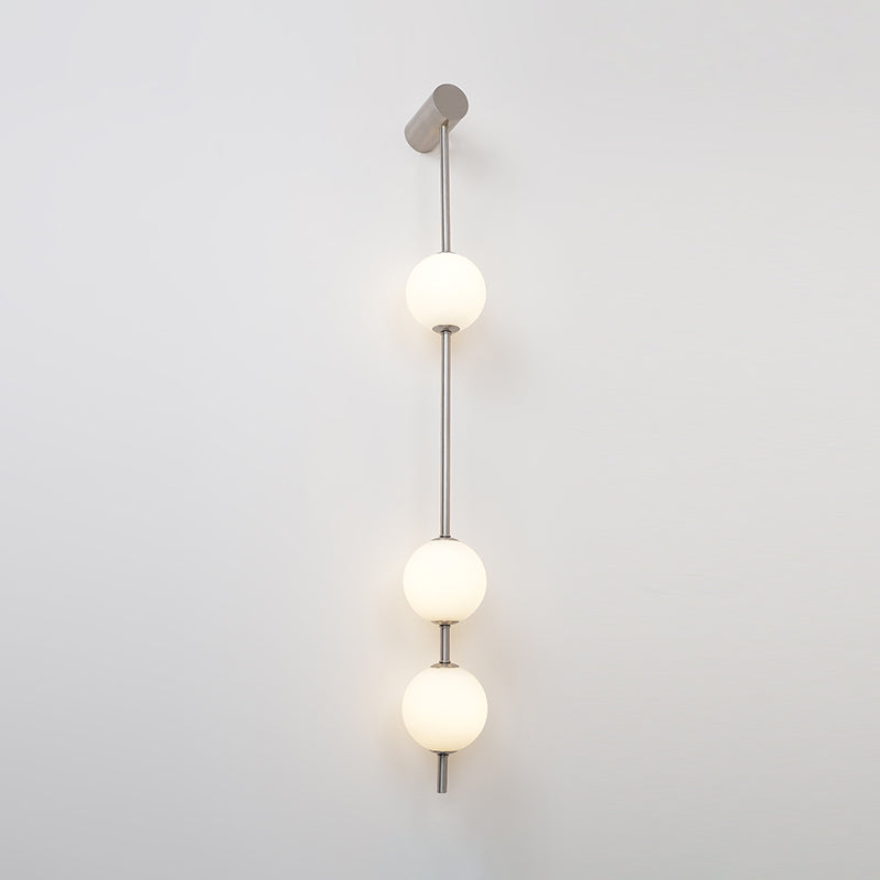 The Clérachic Stacked Globe Wall Sconce in brushed nickel, lit, three globes glowing on a plain white backdrop.